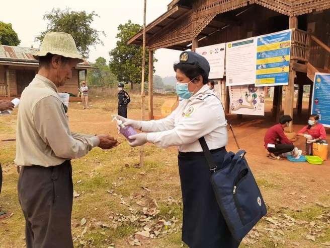 Volunteer providing hand sanitiser to elderly man