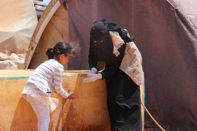 A volunteer training a young girl in hand washing