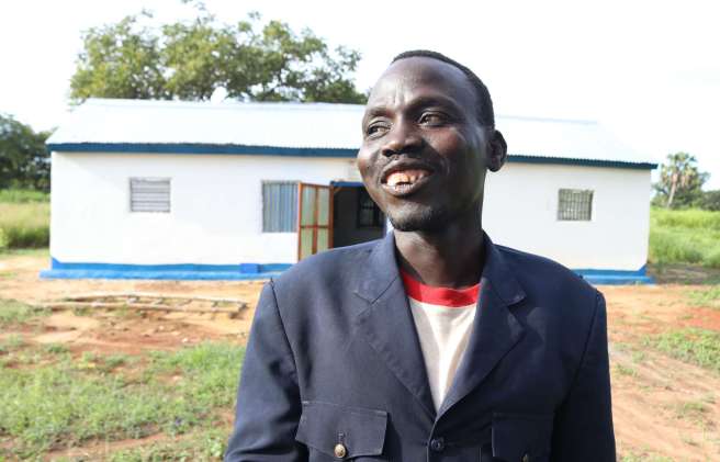 Richard Unguec, 37, stands in front of the newly constructed primary healthcare facility built by the Nyikijo community, South Sudan